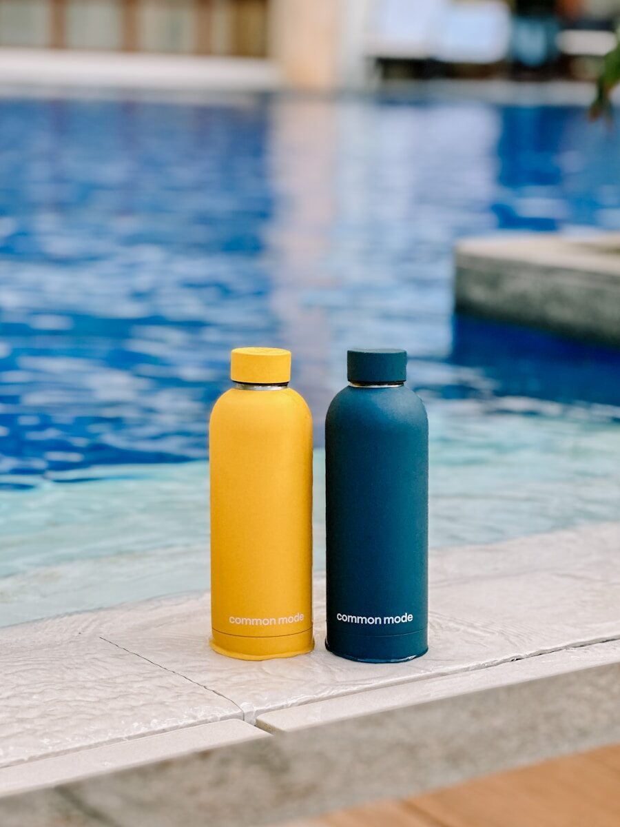 Photo by SJ 📸 two water bottles sitting next to a swimming pool